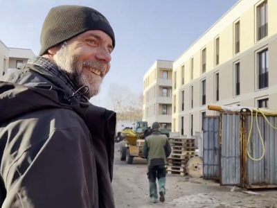 Lächelnder Mann mit Bart und Mütze auf einer Baustelle